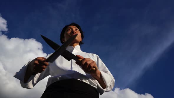 Asian man sharpening knives outside