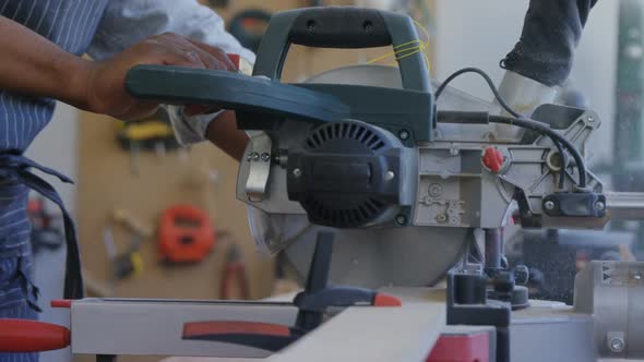 Mid section of carpenter cutting wooden plank with electric saw 4k