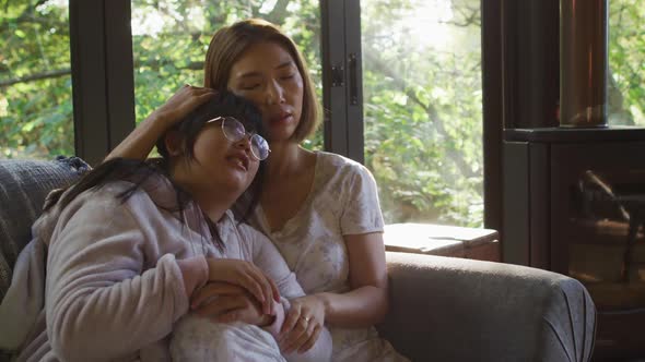 Asian mother and daughter embracing and lying on couch