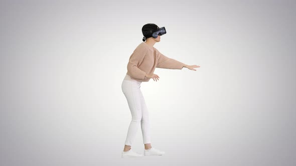 Cute Young Woman Walking and Using Interactive VR Headset on Gradient Background