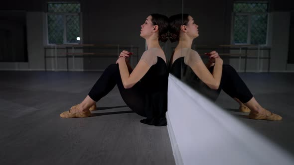 Side View Frustrated Exhausted Ballerina Sitting on Floor at Mirror Putting Head on Knees