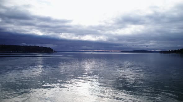 Contrast of dark skies and bright reflections on calm water, Puget Sound, Washington, aerial