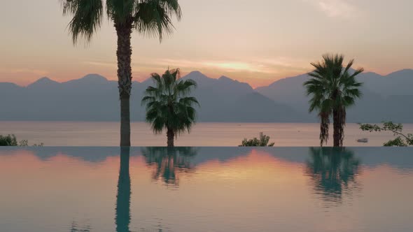 A Steadicam Shot of a Glossy Swimming Pool Boundary and an Evening Sea Landscape on the Background