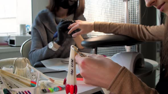 Beauty Salon Visitor Looks at Palette with Coloured Manicure