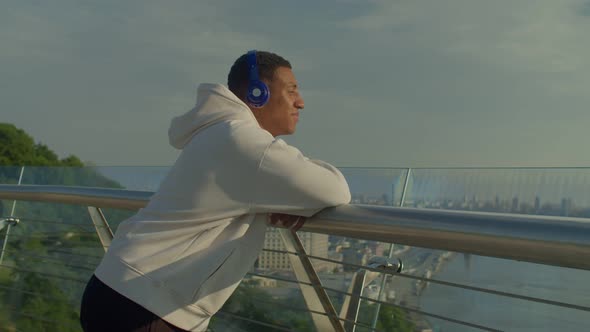 Calm African American Man in Headphones Enjoying Panoramic City View at Dawn