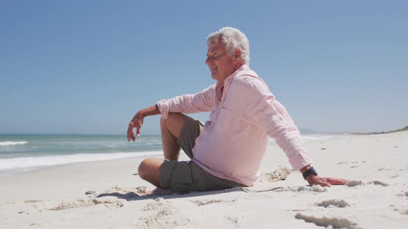Happy senior caucasian man sitting on the beach enjoying the view