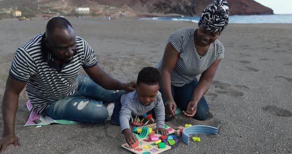 African child having fun with mother and father on the beach