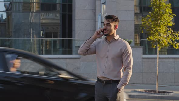Hispanic Business Man Arabic Guy Stands on Street Background of City Buildings Talking on Mobile