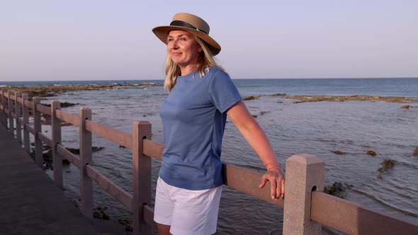 Middle aged woman wearing t-shirt and standing on by the sea