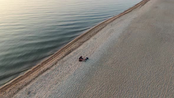 Man playing the guitar on the beach at sunset - aerial view