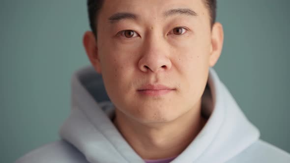 Confident Asian man wearing hoodie opening his eyes at the camera