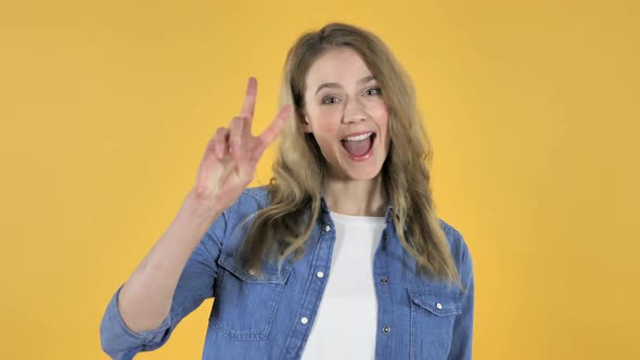 Victory Sign By Young Pretty Girl on Yellow Background