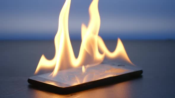 Smartphone is burning on a table on a blue background