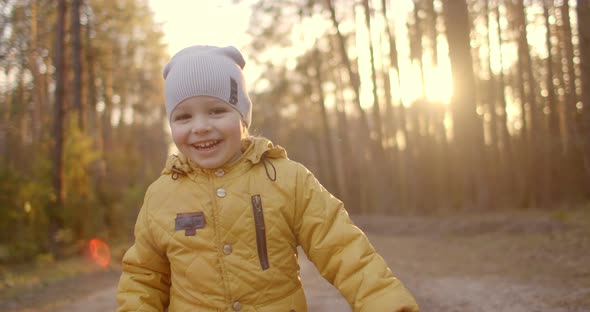 Slow Motion: Young Boy in a Yellow Jacket Explore the World Around Him While Sitting in the Forest