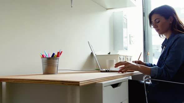 Female executive talking on mobile phone while using laptop