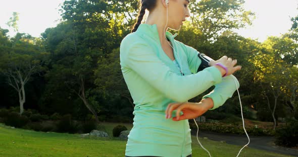 Woman adjusting music settings on armband from smartphone