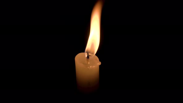 A single white candle burning, central framing close up.