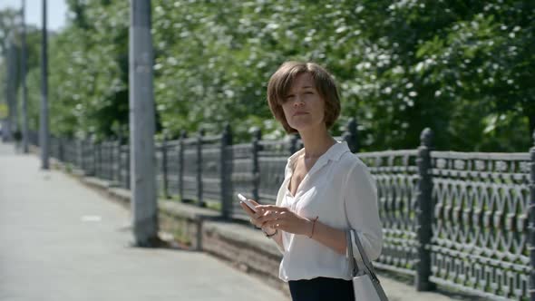 Businesswoman Using Smart Phone and Hailing Taxi in The Street