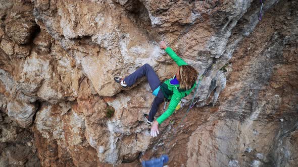Girl Rock Climber Climbs on Rough Crag