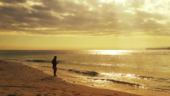 Tourist with fishing rod on beautiful coastline beach voyage by turquoise sea and white sandy backgr