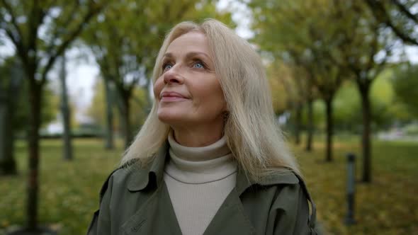 Portrait of Romantic Woman Looking Into Sky Through Trees Branches in Park