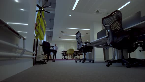 View of a man walking through a well lit modern conference room, preparing for a conference meeting