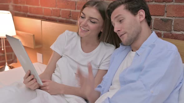 Young Couple Doing Video Chat on Tablet in Bed