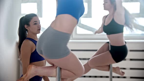 Sportive Women Spinning on the Poles in Bright Studio with Big Window - Their Trainer Watching Them