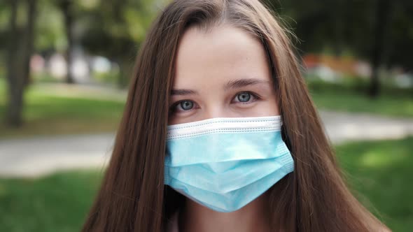 Portrait of a woman about in the city streets during the day, wearing a protective virus face mask.