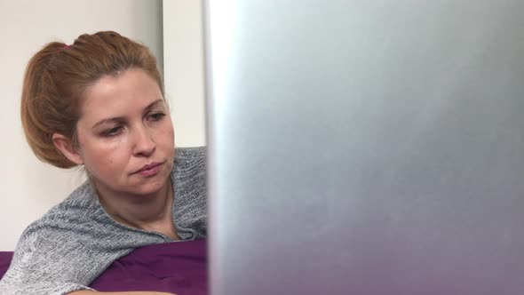 Caucasian woman on mobile computer relaxed in bed  4K 2160p 30fps UltraHD footage - Blond female wor