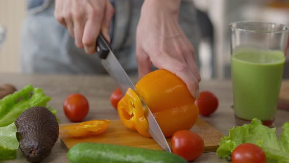 Female Hands Cutting Yellow Bell Pepper with Knife in Wooden Board