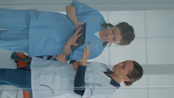 Vertical Video Professional Dentist Talking to Nurse and Looking at Digital Tablet