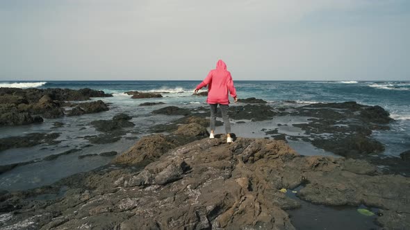 A Woman Walks Next to the Ocean Enjoying the Calm Scenery Against the Background of the Volcanic