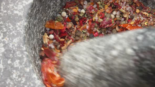 Pestle is Grinding Various Kinds of Spices and Peppers in the Grey Stone Mortar