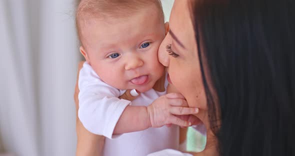 Portrait a Beautiful Woman Looks at Her Newborn Baby and Caresses Him