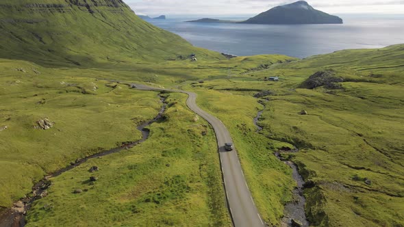 Drone Of Car Driving Along Winding Road In Dramatic Countryside Of Faroe Island