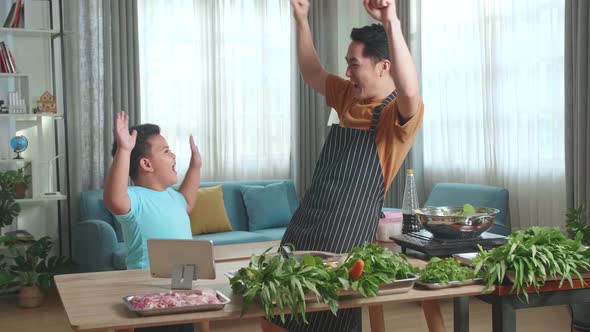 Man Father Giving High Five To Happy Little Child Son While Cooking At Home, They Dancing Together