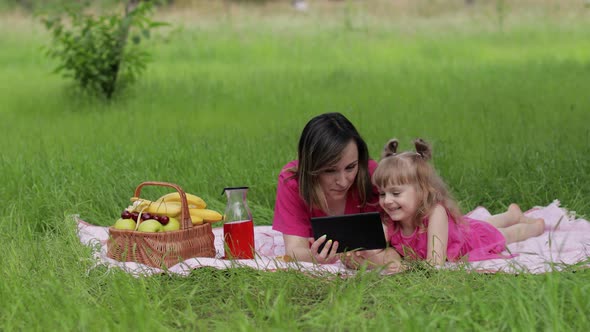 Family Weekend Picnic. Daughter Child Girl with Mother Study Lessons on Tablet. Distance Education