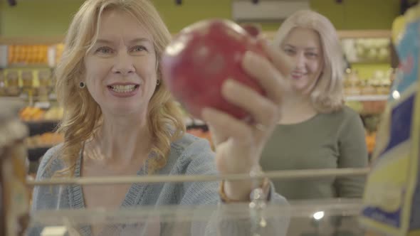 Focus Changes From Juicy Fresh Organic Pomegranate Lying on Shelf in Grocery To Happy Faces of Two