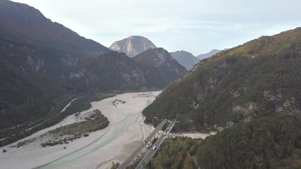 Aerial view of freeway interstate road in italian alps with fast moving traffic and rural green 