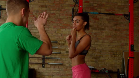 Athletic Woman Boxer Throwing Jab During Training Session with Male Trainer