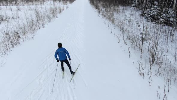 Professional Athlete Skies Along Snowy Track Among Forest