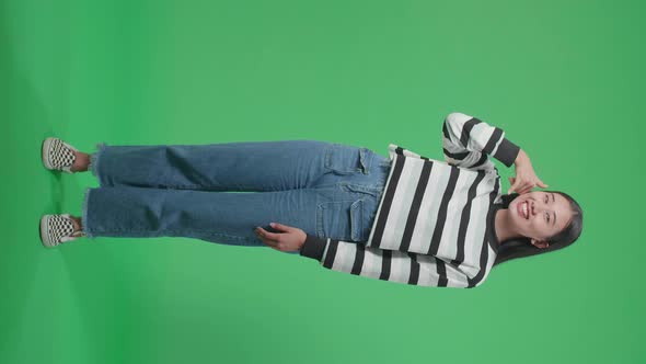 Full Body Of Asian Woman Making A Phone Call Hand Gesture While Standing On Green Screen