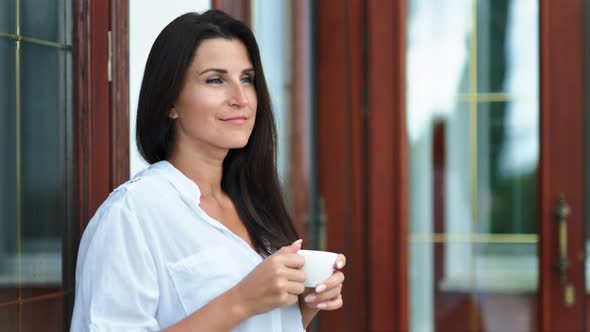 Handsome Brunette Woman Drinking Hot Tea or Coffee Holding White Porcelain Cup By Hands