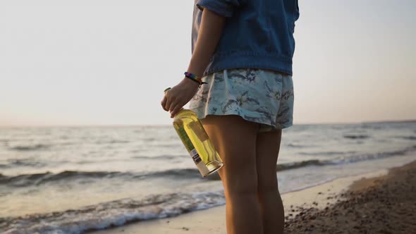 Young LGBTQ Woman Wears Rainbow Bracelet and and Holds Bottle of Wine