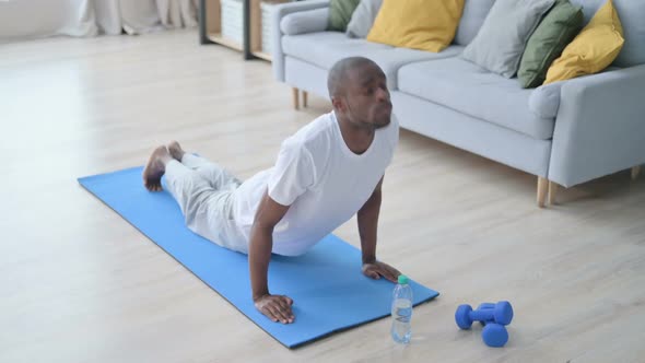 Young African Man Doing Upward Facing Dog Pose on Yoga Mat