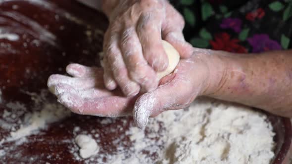 Wrinkled Hands of an Elderly Man Knead the Dough and Make Balls of Kolobok