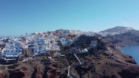 Flight over of traditional terraced white villas ini village Oia, Santorini, Greece