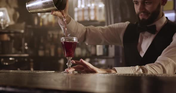 Close-up Shooting. Bartender Is Pouring the Alcohol From the Shaker Through a Cocktail Strainer Into