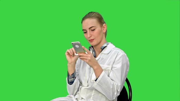 Young Woman Surgeon Doctor Reading SMS on Cell Phone on a Green Screen, Chroma Key